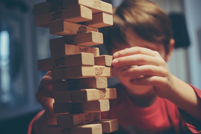 A child pulls a Jenga block from a tower of blocks