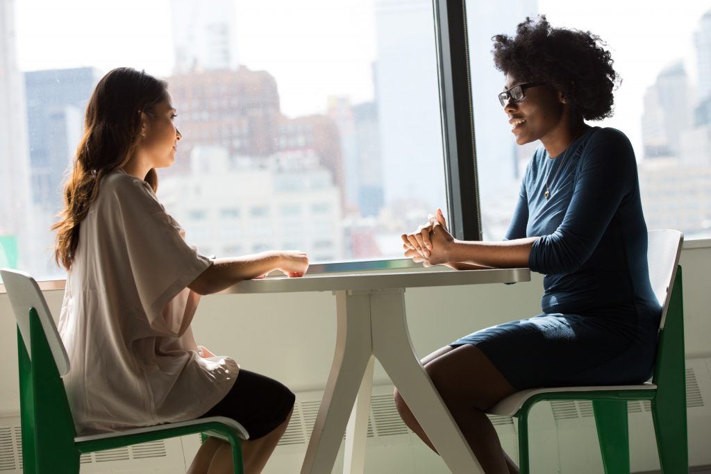 Two women sit at a table talking