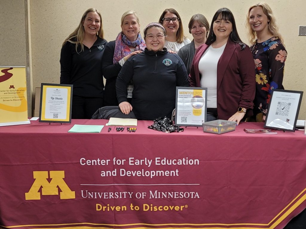 TARSS staff smiling behind a table with a maroon-and-gold tablecloth featuring the Center for Early Education and Development wordmark